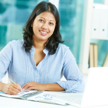 Portrait of happy mature businesswoman looking at camera while working in office